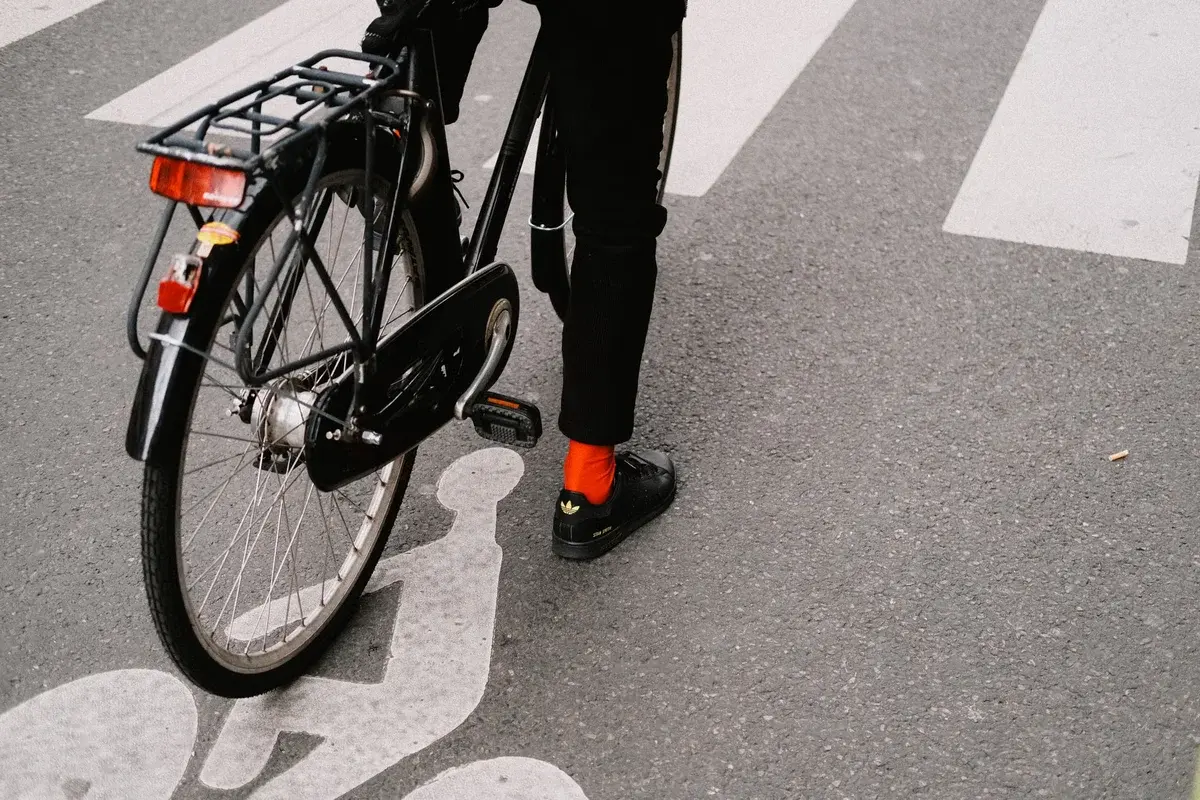 Cyclist in black pants and red socks with black bicycle on city street