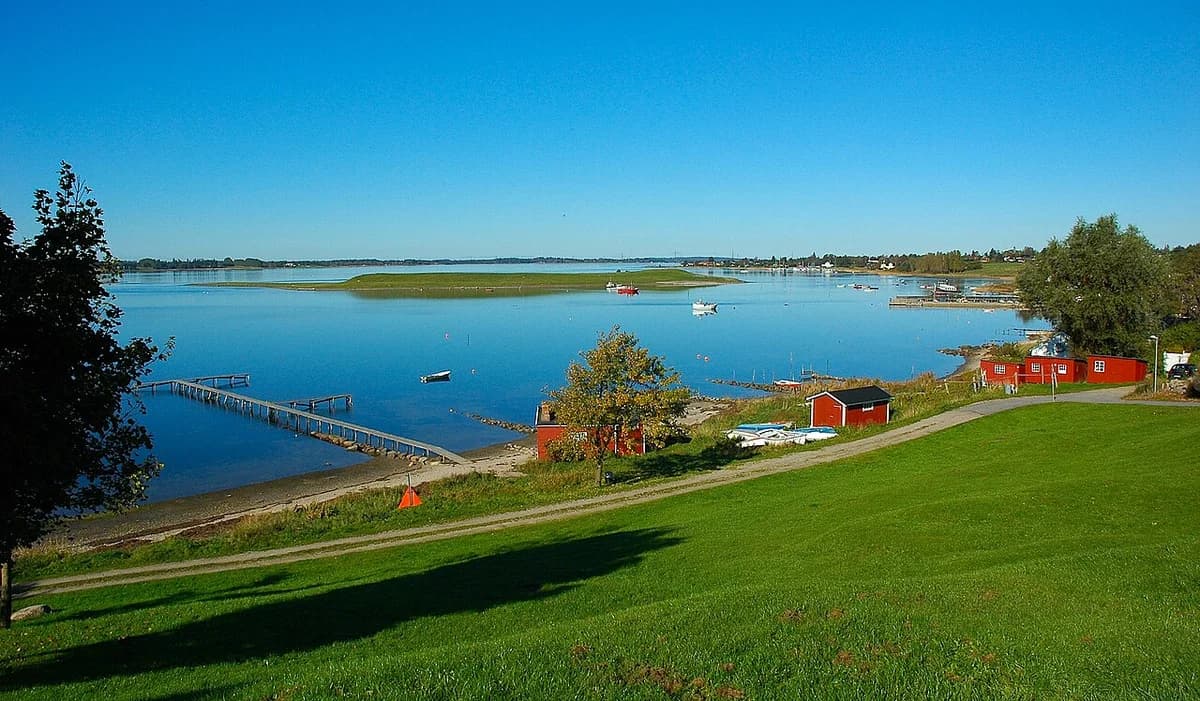 Scenic view of Roskilde Fjord with calm water, boats, and grassy shoreline near Jyllinge.