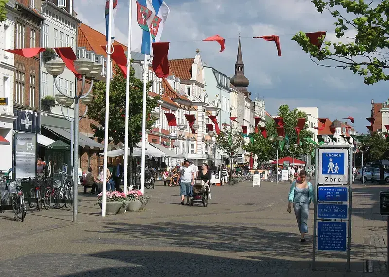 Pedestrian street in Horsens with shops, flags, and people walking