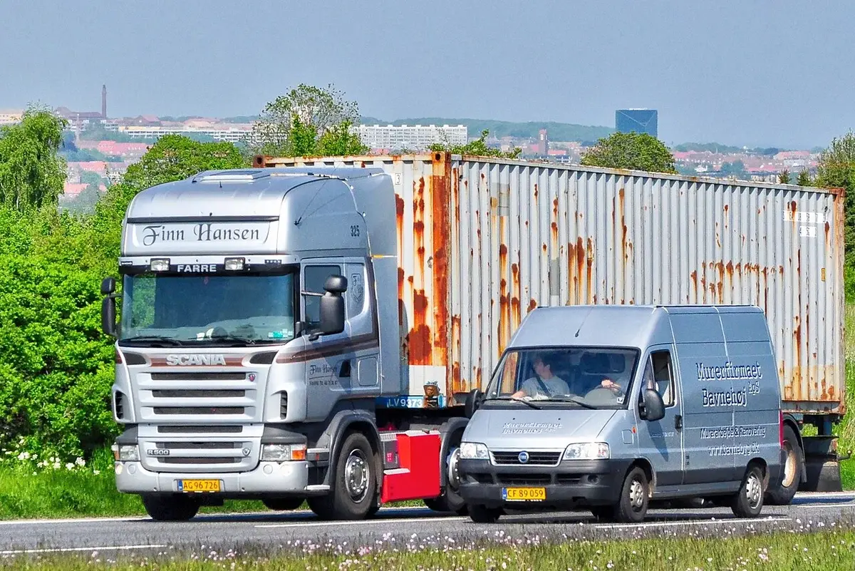 A Scania truck and a gray van driving on a road near Aarhus.