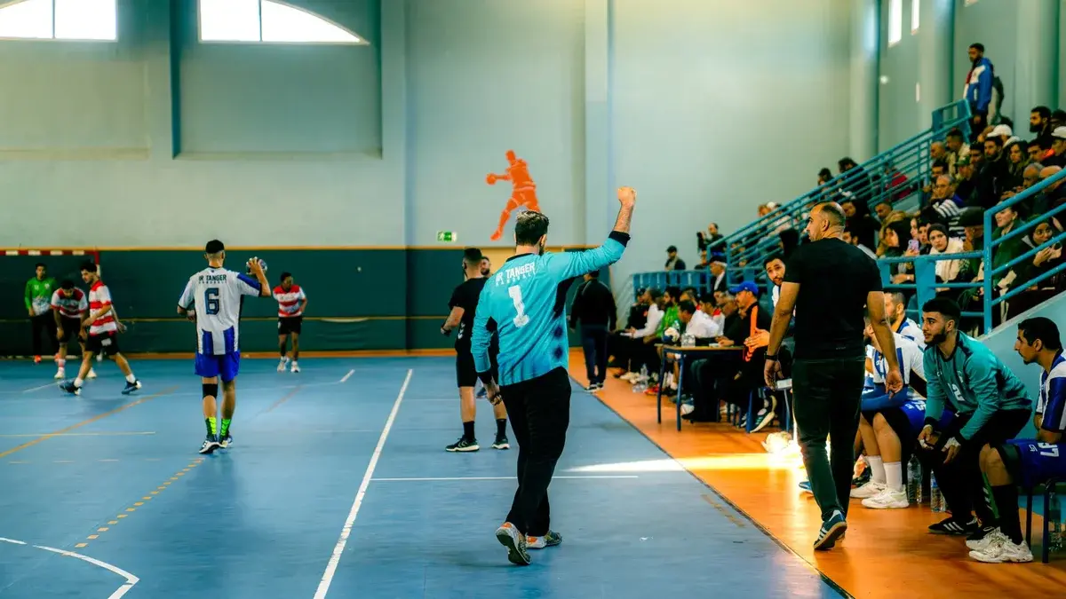 Handball players in action with spectators in a gymnasium