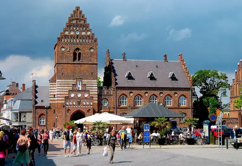 Historic red-brick town gate with people and cafés in front