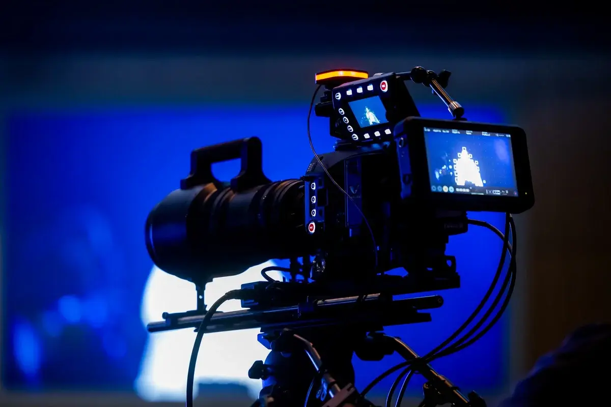 Video camera rig with monitor screens in a blue-lit studio