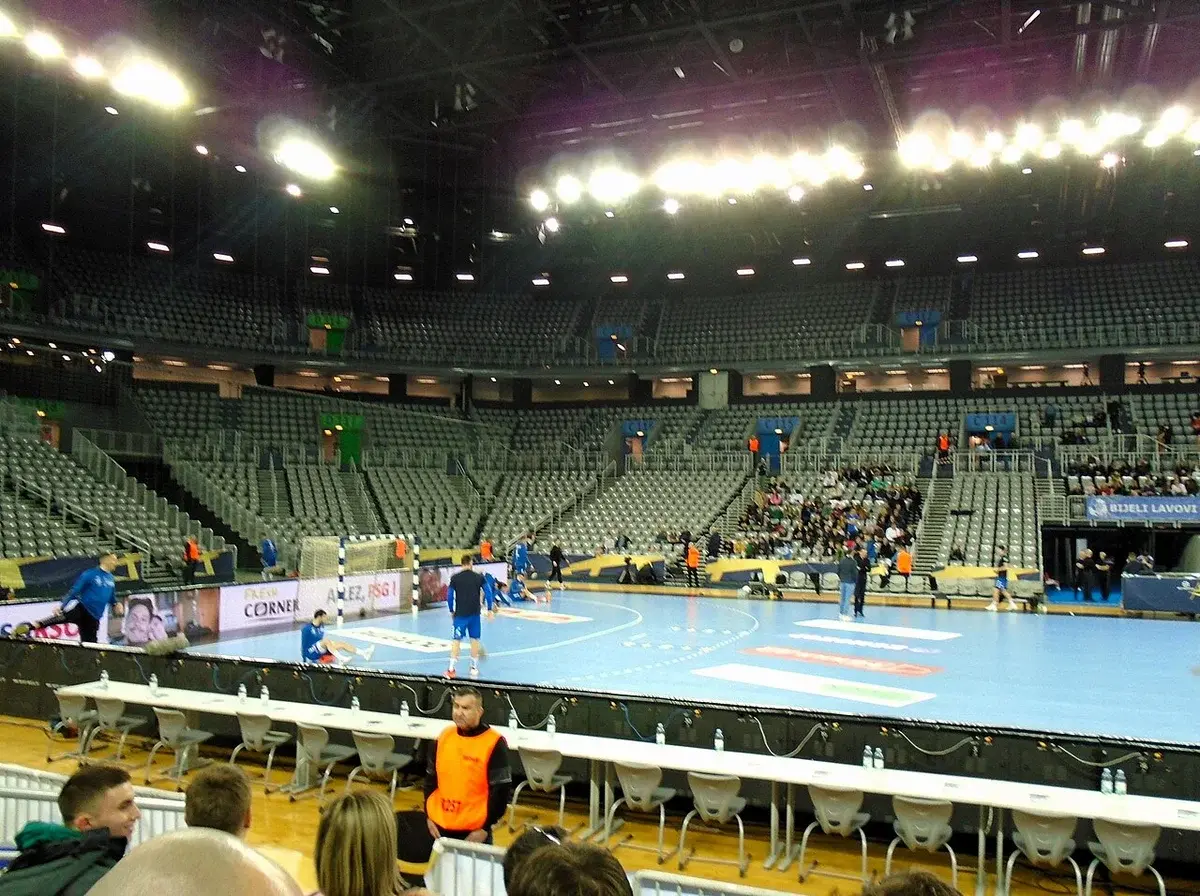 Handball players warming up in an indoor arena before a match.