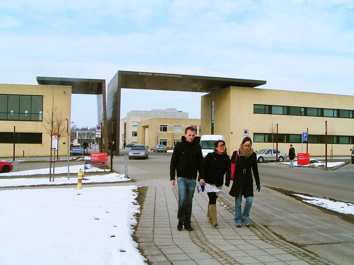 Exterior view of Roskilde University with three people walking outside