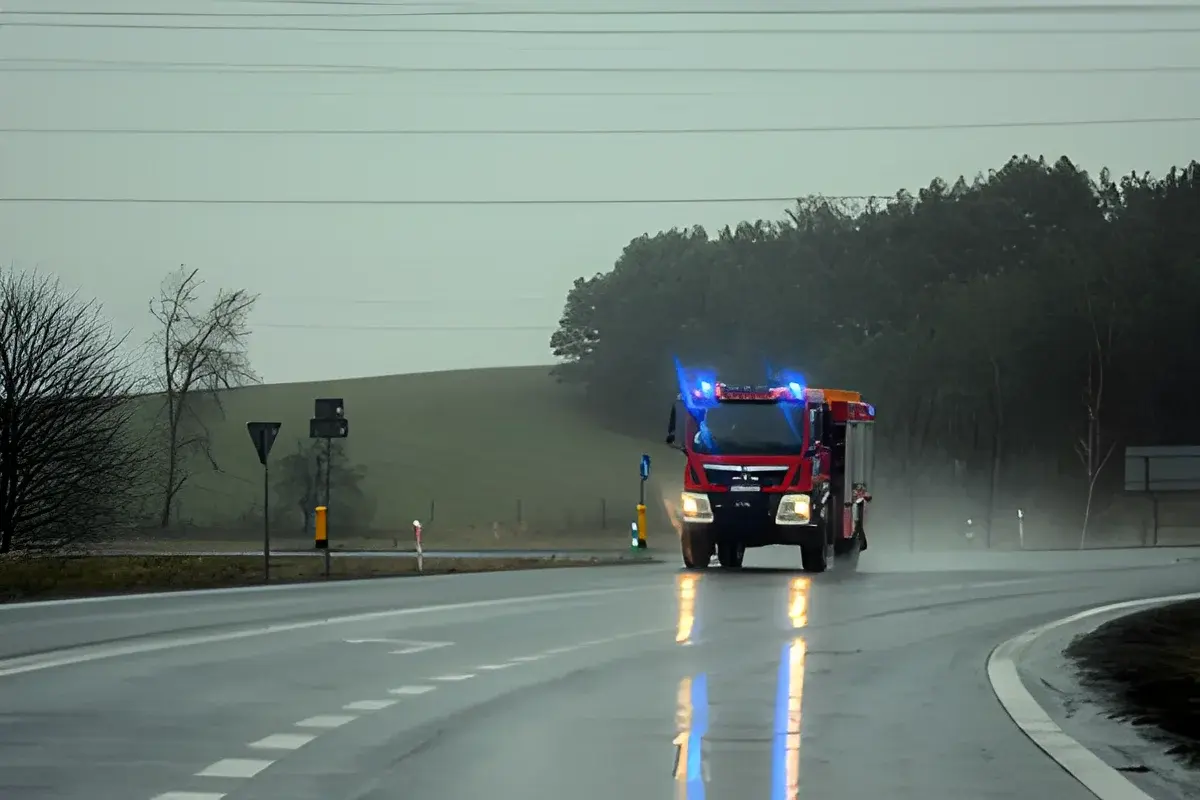 Fire truck driving on a wet road with flashing lights.