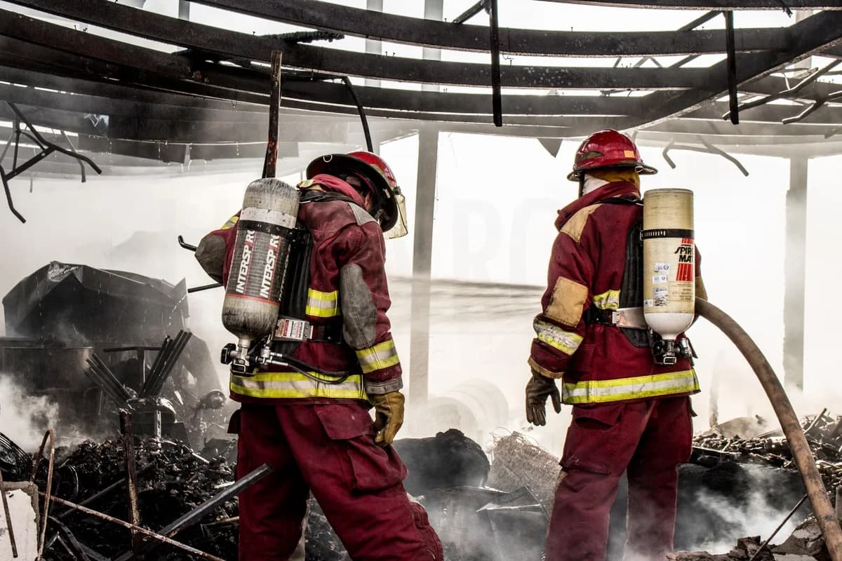 Two firefighters battle a fire inside a burned building.
