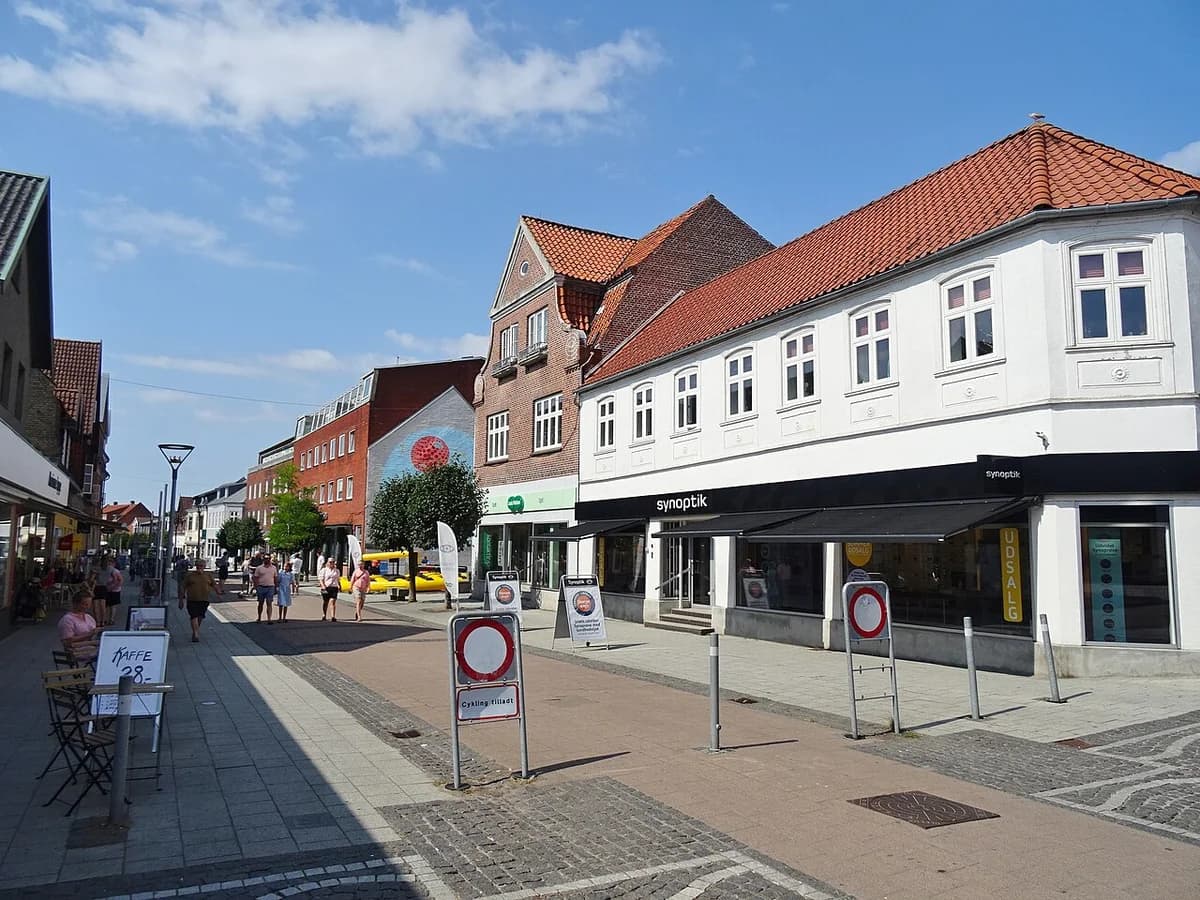 A pedestrian shopping street with shops and people in Vordingborg, Denmark.