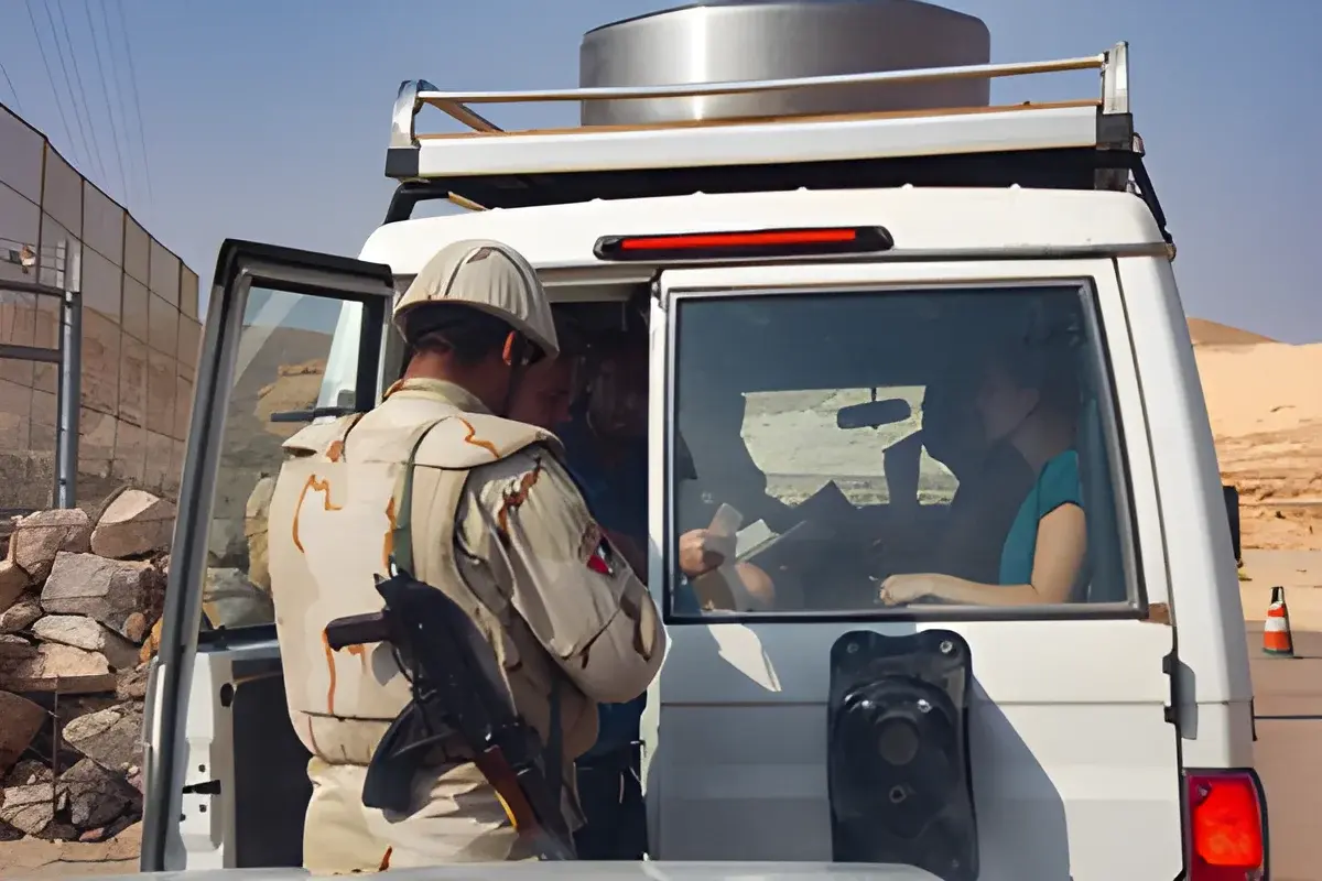 Armed border control officer checking passports inside vehicle at checkpoint