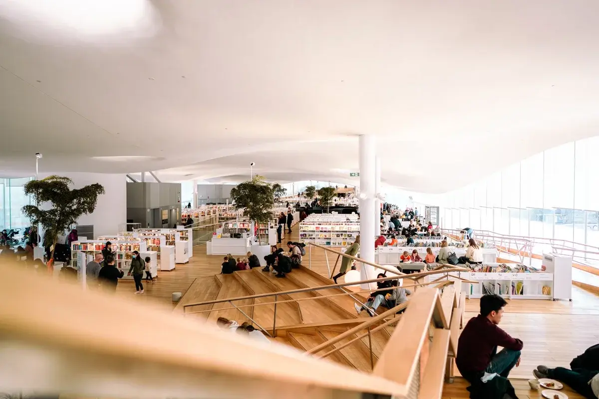 People reading and relaxing in a bright modern library interior.