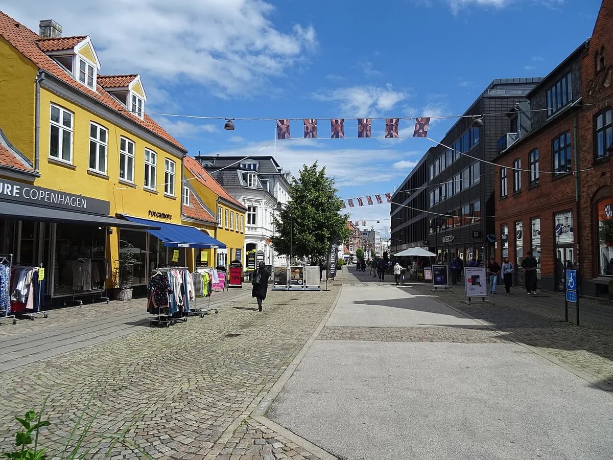 A shopping street in Roskilde, Denmark, with shops and pedestrians.
