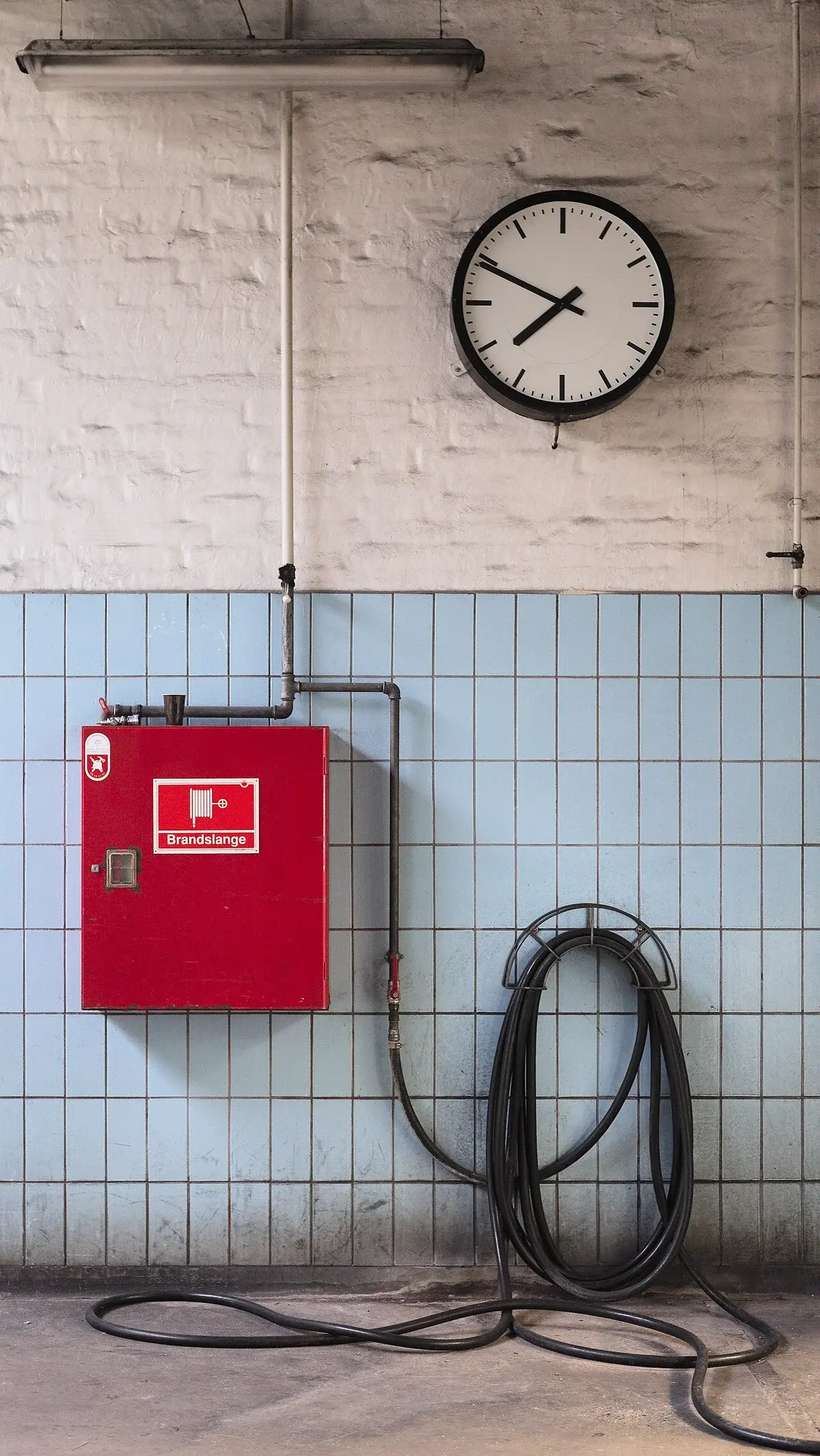 Fire hose cabinet and wall clock on tiled wall