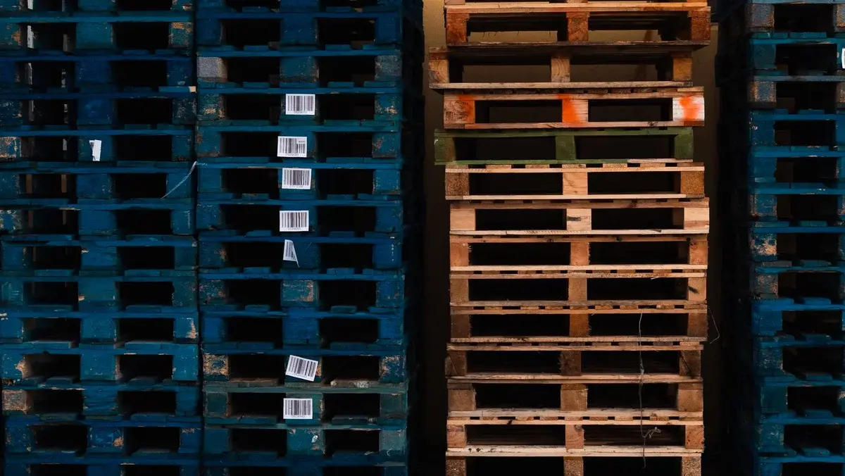 Stacks of wooden pallets with barcodes in a warehouse.