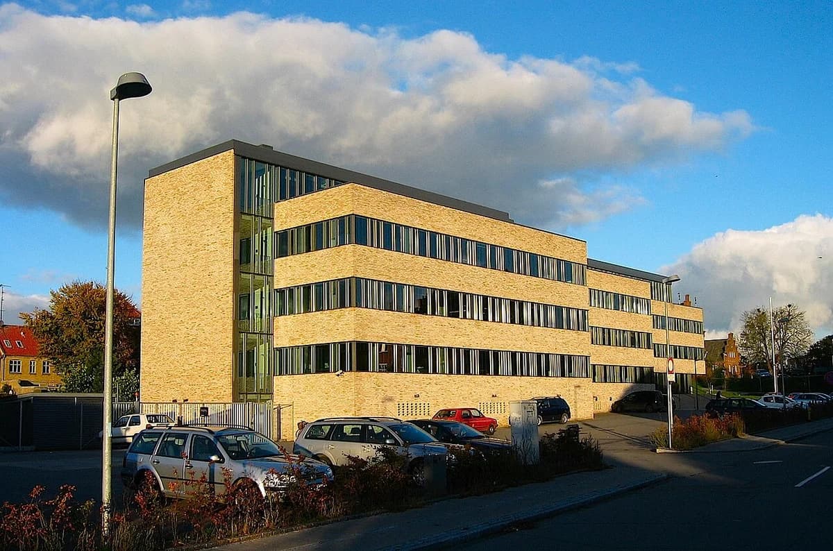 Modern police headquarters building in Roskilde with several parked cars