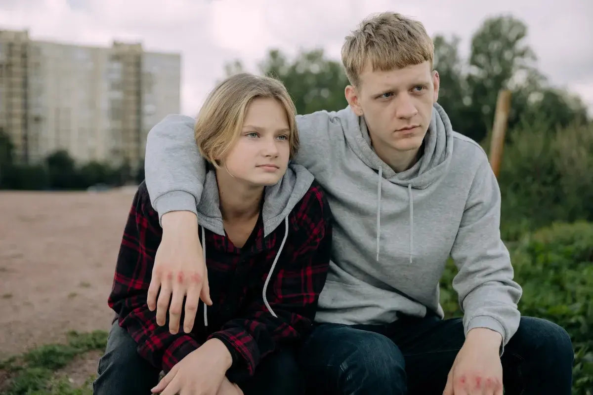 two siblings sitting together outdoors