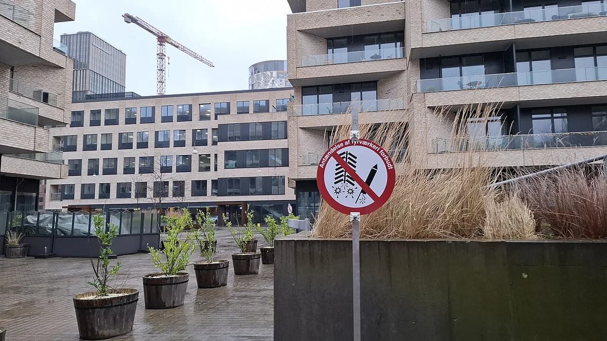 A fireworks prohibition sign in a modern plaza with apartment buildings behind it.