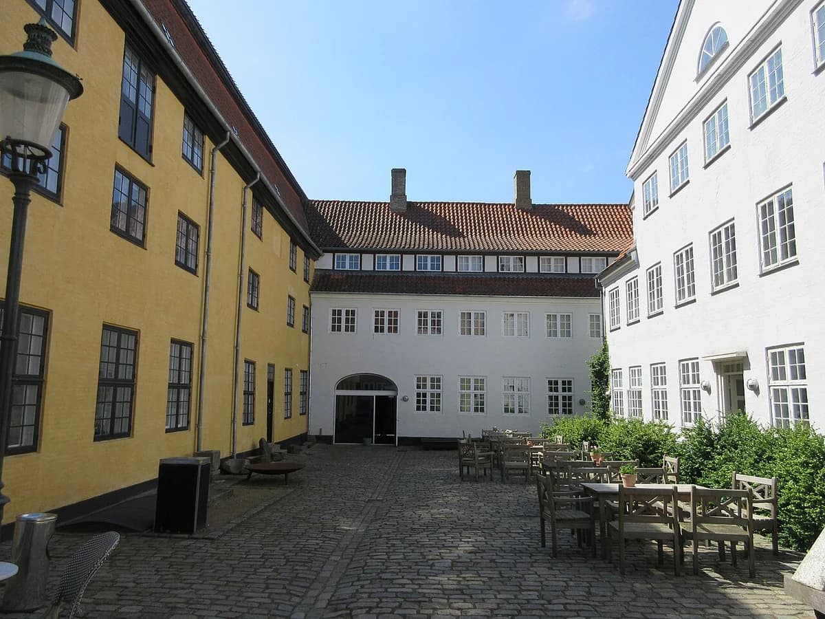 Courtyard with cobblestone ground, yellow and white buildings, and outdoor seating
